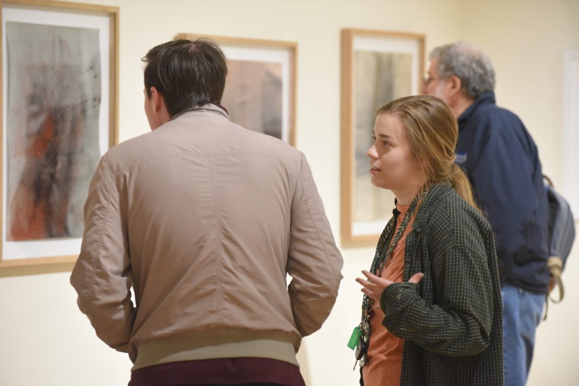 Students examine artwork on view in the Lykes Atrium.